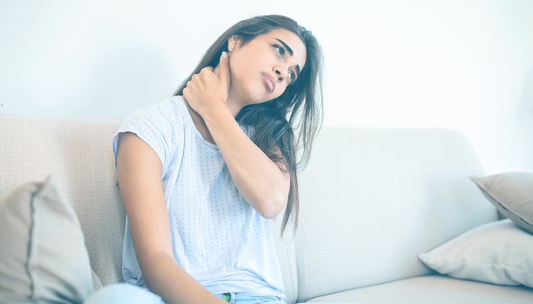 mujer con la mano en las cervicales y cara de dolor por latigazo cervical, la mujer quiere calcular la indemnizacion por latigazo cervical